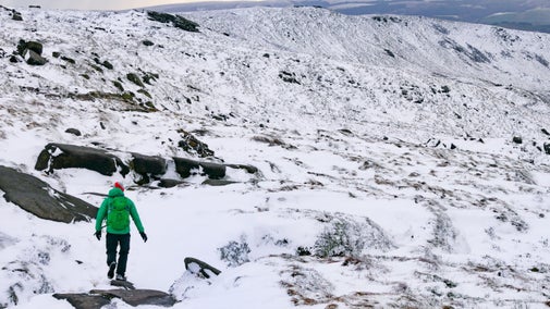 Lone walker on a snowy hillside at Kinder Scout, Derbyshire